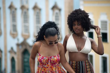 Arka planda eski evlere karşı yan yana duran iki genç arkadaş. Yolculukta insanları güçlendirdi. Brezilya