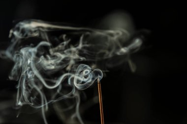 Siyah bir arkaplanda tütsüyü dumanla yakmak. Stüdyo çekimi.