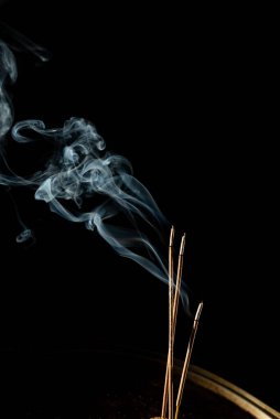 Siyah arka planda duman olan üç yanan tütsü çubuğu. Stüdyo çekimi.