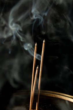 Siyah arka planda duman olan üç yanan tütsü çubuğu. Stüdyo çekimi.