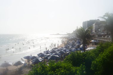 Salvador, Bahia, Brezilya - 05 Ocak 2025: İnsanlar güçlü güneş ışığı altında Farol da Barra plajında eğlenirken görülüyor. Salvador, Bahia. 