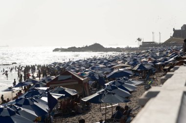 Salvador, Bahia, Brezilya - 05 Ocak 2025: İnsanlar güçlü güneş ışığı altında Farol da Barra plajında eğlenirken görülüyor. Salvador, Bahia. 