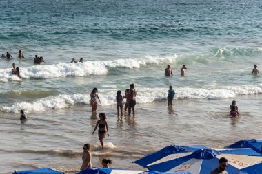 Salvador, Bahia, Brezilya - 05 Ocak 2025: İnsanlar güçlü güneş ışığı altında Farol da Barra plajında eğlenirken görülüyor. Salvador, Bahia. 