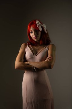 Siyah arka planda fotoğraf için pembe elbiseli genç bir kadın poz veriyor. Stüdyo resmi