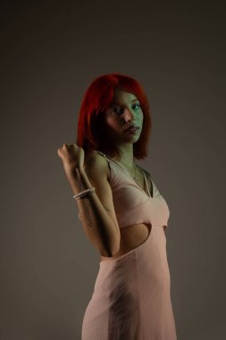 Genç, güzel, kızıl saçlı kız arka planda fotoğraf için poz veriyor. Stüdyo resmi.