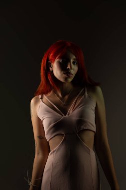 Genç, güzel, kızıl saçlı kız arka planda fotoğraf için poz veriyor. Stüdyo resmi.