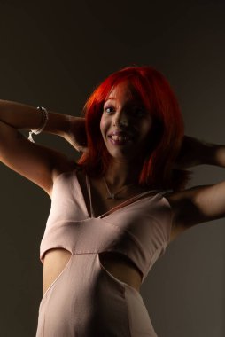 Genç, güzel, kızıl saçlı kız arka planda fotoğraf için poz veriyor. Stüdyo resmi.