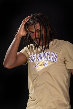 Salvador, Bahia, Brezilya - 3 Mayıs 2025: Sıradan kıyafetler giyen ve eli saçı olan yakışıklı bir gencin stüdyo portresi. Siyah arka planda izole edilmiş. Kendine güvenen biri..