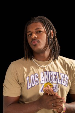 Salvador, Bahia, Brezilya - 3 Mayıs 2025: Sıradan kıyafetler giyen ve kameraya poz veren yakışıklı genç adamın stüdyo portresi. Siyah arka planda izole edilmiş. Kendine güvenen biri..