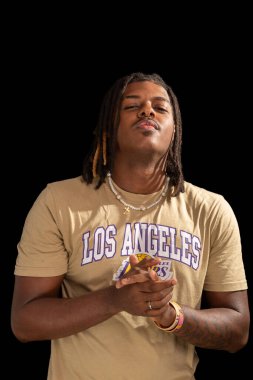 Salvador, Bahia, Brezilya - 3 Mayıs 2025: Sıradan kıyafetler giyen ve kameraya poz veren yakışıklı genç adamın stüdyo portresi. Siyah arka planda izole edilmiş. Kendine güvenen biri..