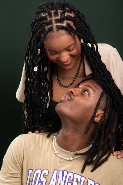 Сальвадор, Баия, Бразилия - 03 мая 2025 года: Портрет пары влюбленных вместе в повседневной одежде. Он сидит, а она стоит за ним. Любимые люди. Изолированный на темно-зеленом фоне.