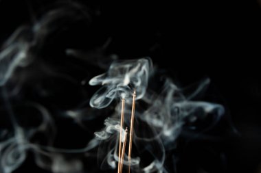 Siyah arka planda duman olan üç yanan tütsü çubuğu. Stüdyo çekimi.