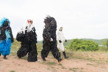 Korkunç kostümler ve maskeler giymiş bir grup kimliği belirsiz insan kırsal bir bölgede yürüyor. Brezilya 'da karnaval günü.