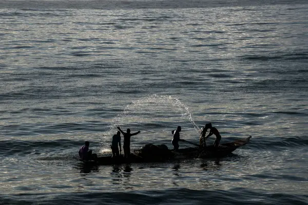 Tanımlanamayan balıkçılar gölgede kanoda balık ağı atıyorlar. Balıkçılık hobisi. Brezilya