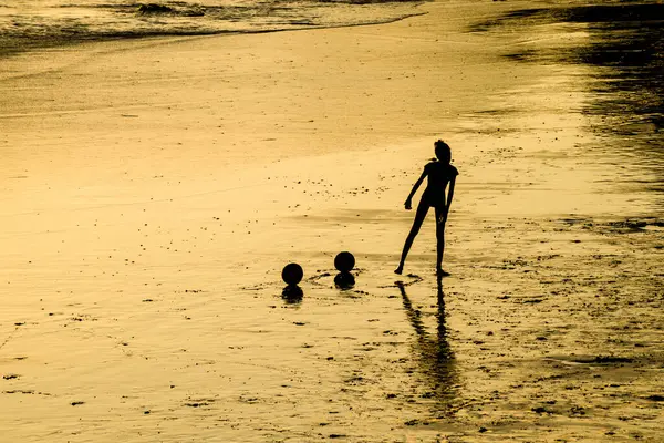 Salvador, Bahia, Brezilya - 22 Aralık 2019: Bahia 'nın Salvador şehrinde günbatımında plaj futbolu oynayan genç adam.