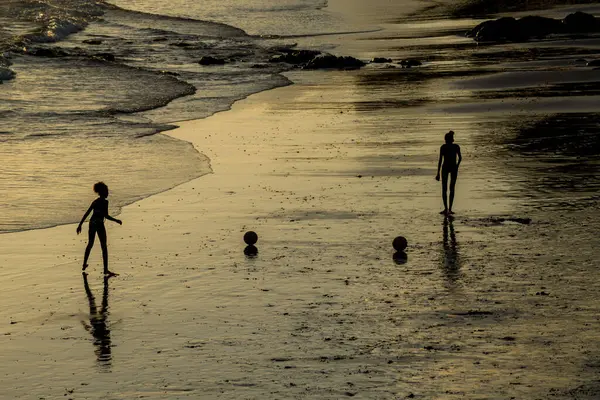 Salvador, Bahia, Brezilya - 22 Aralık 2019: Gençler gün batımında plajda eğlenirken görülüyor. Salvador, Bahia.