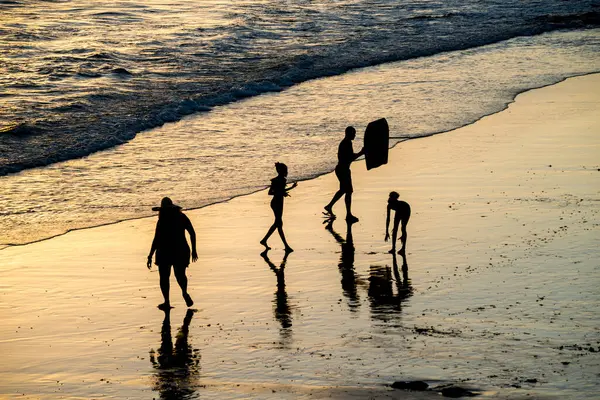 Salvador, Bahia, Brezilya - 22 Aralık 2019: Gençler gün batımında plajda eğlenirken görülüyor. Salvador, Bahia.