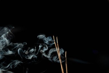 Siyah arka planda duman olan üç yanan tütsü çubuğu. Stüdyo çekimi.