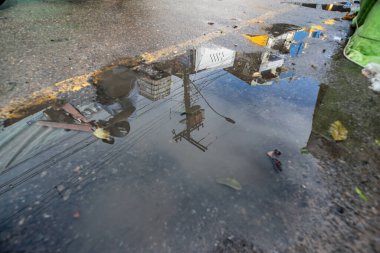 Salvador, Bahia, Brezilya - 18 Mayıs 2025: Santo Amaro, Bahia 'da sokak, ev ve insanların yansıması ile bir su birikintisi oluşturan yağmur suyu manzarası.
