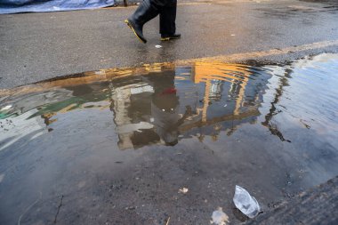 Salvador, Bahia, Brezilya - 18 Mayıs 2025: Santo Amaro, Bahia 'da sokak, ev ve insanların yansıması ile bir su birikintisi oluşturan yağmur suyu manzarası.