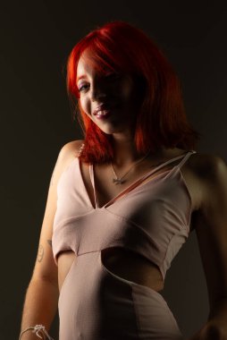 Genç, güzel, kızıl saçlı kız arka planda fotoğraf için poz veriyor. Stüdyo resmi.