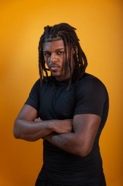 Siyah elbiseli yakışıklı bir gencin stüdyo portresi ve portakal renkli arka planda poz vermesi. Kendine güvenen ve sakin biri..