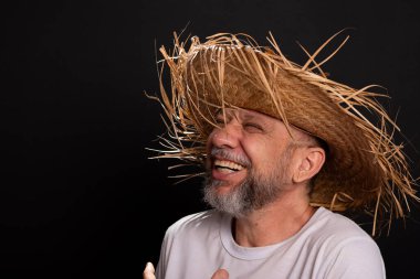 Brezilya 'daki Sao Joao festivalindeki bir karakteri temsil eden beyaz tişörtlü ve hasır şapkalı sakallı bir adam. Geleneksel festival.