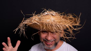 Brezilya 'daki Sao Joao festivalindeki bir karakteri temsil eden beyaz tişörtlü ve hasır şapkalı sakallı bir adam. Geleneksel festival.