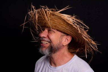 Brezilya 'daki Sao Joao festivalindeki bir karakteri temsil eden beyaz tişörtlü ve hasır şapkalı sakallı bir adam. Geleneksel festival.