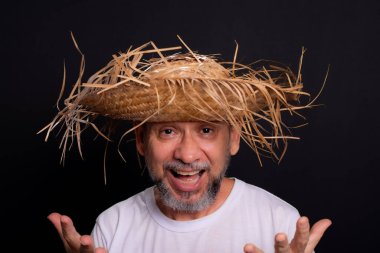 Brezilya 'daki Sao Joao festivalindeki bir karakteri temsil eden beyaz tişörtlü ve hasır şapkalı sakallı bir adam. Geleneksel festival.