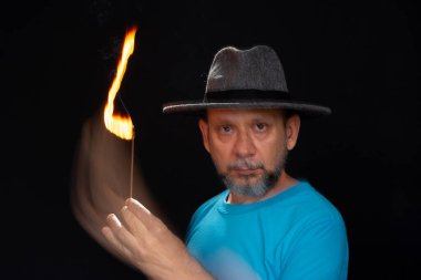 Mavi gömlekli, sakallı kel bir adamın sanatsal portresi. Yanan tütsüyle hafif izler bırakıyor. Hareket bulanıklığı. Siyah arkaplan.