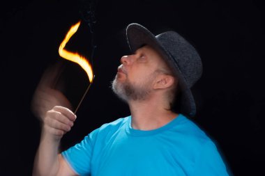 Mavi gömlekli, sakallı kel bir adamın sanatsal portresi. Yanan tütsüyle hafif izler bırakıyor. Hareket bulanıklığı. Siyah arkaplan.