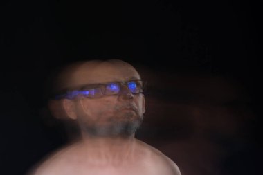 Hareket bulanıklığı efektli güneş gözlüğü takan sakalsız kel adamın sanatsal portresi. Siyah arkaplan.