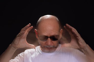 Beyaz gömlekli sakallı kel adamın sanatsal portresi elleri ve kollarıyla hareket bulanıklığı yaratıyor. Siyah arkaplan.