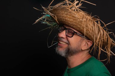 Brezilya 'daki Sao Joao festivali için hasır şapkalı ve yeşil gömlekli gülümseyen sakallı adam. Ülke partisi