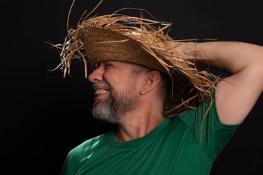 Brezilya 'daki Sao Joao festivali için hasır şapkalı ve yeşil gömlekli gülümseyen sakallı adam. Ülke partisi