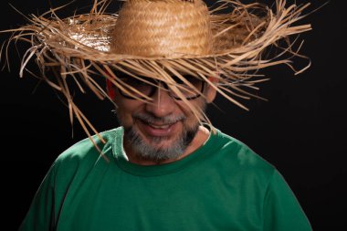 Brezilya 'daki Sao Joao festivali için hasır şapkalı ve yeşil gömlekli gülümseyen sakallı adam. Ülke partisi