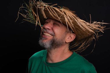 Brezilya 'daki Sao Joao festivali için hasır şapkalı ve yeşil gömlekli gülümseyen sakallı adam. Ülke partisi