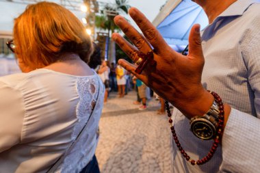 Salvador, Bahia, Brezilya - 27 Aralık 2019: Senhor do Bonfim kilisesinde yapılan açık hava ayini sırasında dua eden Katoliklerin elleri. Salvador, Brezilya.