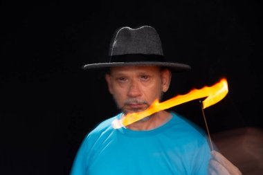 Mavi gömlekli, sakallı kel bir adamın sanatsal portresi. Yanan tütsüyle hafif izler bırakıyor. Hareket bulanıklığı. Siyah arkaplan.