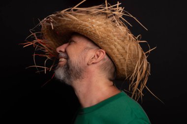 Brezilya 'daki Sao Joao festivali için hasır şapkalı ve yeşil gömlekli gülümseyen sakallı adam. Ülke partisi