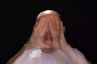 Beyaz gömlekli sakallı kel adamın sanatsal portresi elleri ve kollarıyla hareket bulanıklığı yaratıyor. Siyah arkaplan.