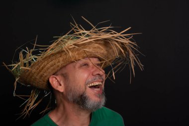 Brezilya 'daki Sao Joao festivali için hasır şapkalı ve yeşil gömlekli gülümseyen sakallı adam. Ülke partisi