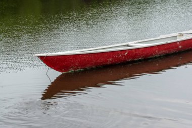 Yağmurlu bir günde kırmızı bir balıkçı kanosu nehirde durdu. Yaşam biçimi.