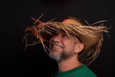 Brezilya 'daki Sao Joao festivali için hasır şapkalı ve yeşil gömlekli gülümseyen sakallı adam. Ülke partisi