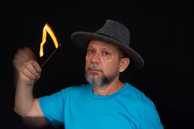 Mavi gömlekli, sakallı kel bir adamın sanatsal portresi. Yanan tütsüyle hafif izler bırakıyor. Hareket bulanıklığı. Siyah arkaplan.