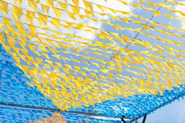 Haziran şenliklerini süsleyen renkli afişler. Plastik nesneler yukarıda asılı. Pelourinho, Brezilya.