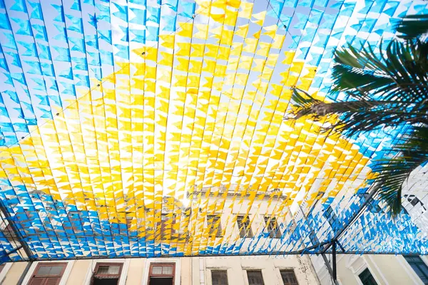 Haziran şenliklerini süsleyen renkli afişler. Plastik nesneler yukarıda asılı. Pelourinho, Brezilya.