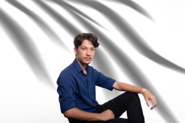 Siyah saçlı, mavi gömlekli, oturan ve kameraya ciddi ciddi bakan genç ve yakışıklı bir öğrenci. Kendine güvenen biri. Profesyonel konsept.