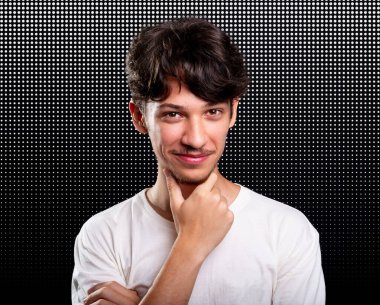 Beyaz gömlekli yakışıklı bir genç tek eliyle çenesine dokunuyor. Stüdyo çekimi